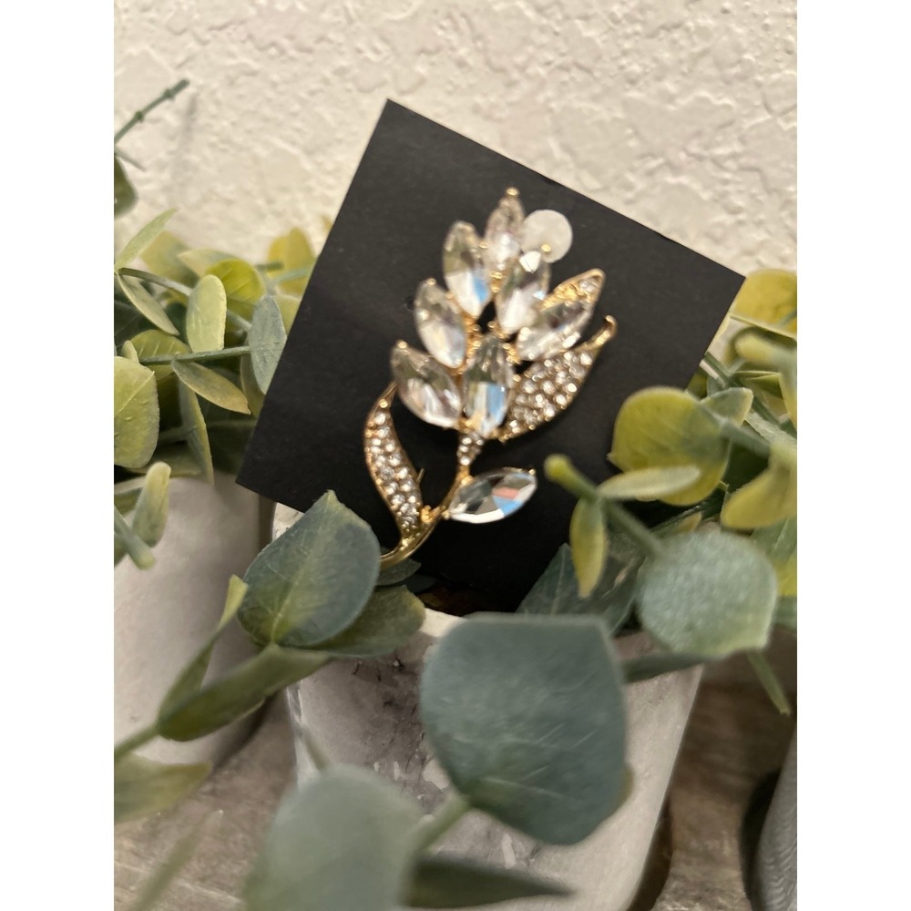 Vintage brooch features a gold-tone metal leaf and flower design